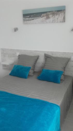Elle comprend un grand lit avec des oreillers bleus. dans l'établissement Appartement 6-8 personnes- 3 chambres- proche de tout à pied, à La Chaume