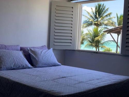 Un dormitorio con una gran ventana con una palmera en Casa de frente para o mar (Front beach house), en Cabedelo