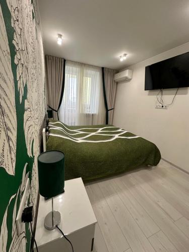 een slaapkamer met een groen bed en een tv bij Jungle Apartments in Vinnytsya