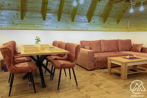 a living room with a couch and a table and chairs at Vila Marija HP in Han Pijesak