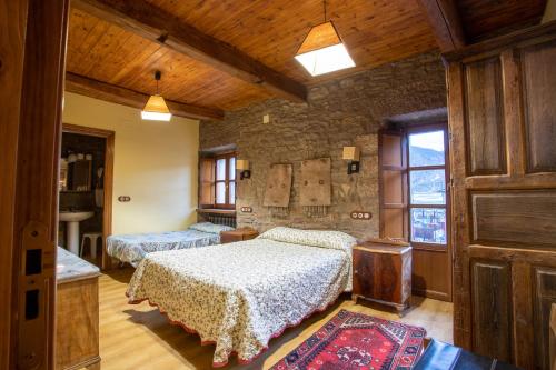 a bedroom with two beds and a stone wall at Casa Rural Anita in Cabrillanes