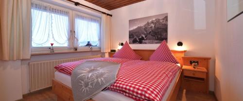 a bedroom with a red and white bed and windows at Panoramablick Ferienwohnungen in Fischen