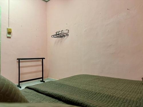 - une chambre avec un lit et un cintre sur le mur dans l'établissement Teratak Tok Ma Rumah Nyatuh, à Kampong Wakaf Tengah