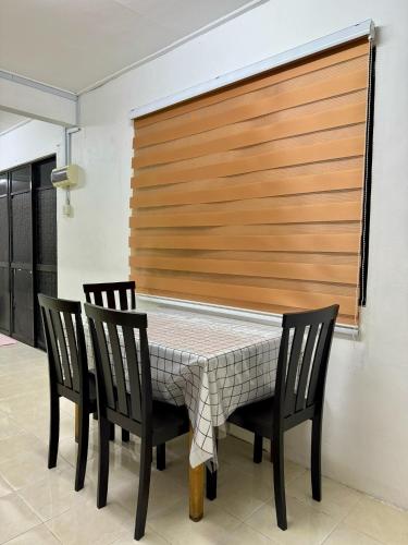 - une salle à manger avec une table et quatre chaises dans l'établissement Teratak Tok Ma Rumah Nyatuh, à Kampong Wakaf Tengah