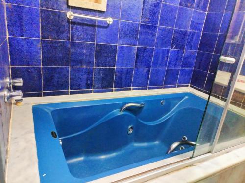 a blue tub in a bathroom with blue tiles at EcoHotel Vale do Sol in Embu