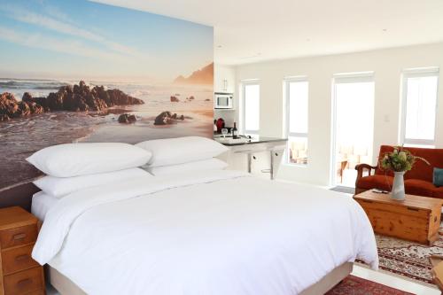 1 dormitorio con 1 cama blanca y una pintura en la pared en Nivenia Beach House en Bettyʼs Bay