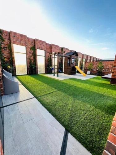 a grassy yard with a playground in front of a building at Apartamento 3 Habitaciones, Edificio Airali, Zona 10, Avellino in Guatemala