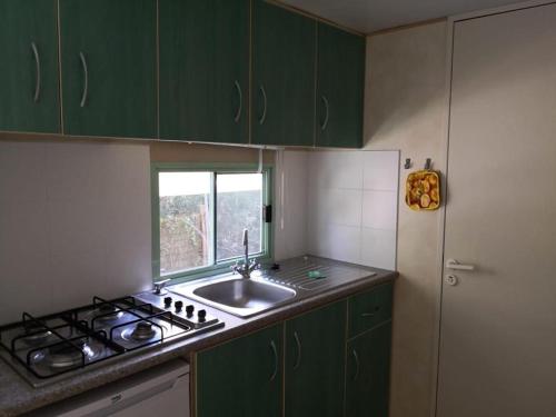 een keuken met groene kasten, een wastafel en een raam bij Il Bungalow in Follonica