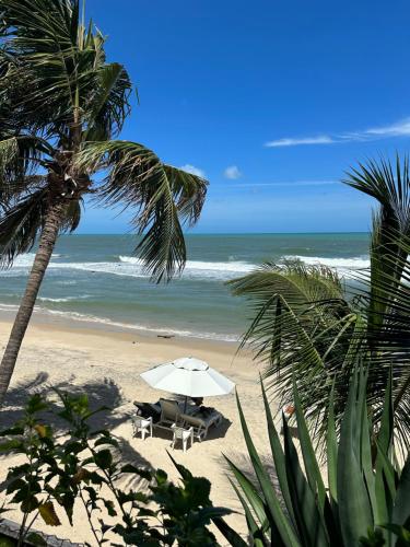 a beach with chairs and an umbrella and the ocean at Hotel Casablanca in Pipa