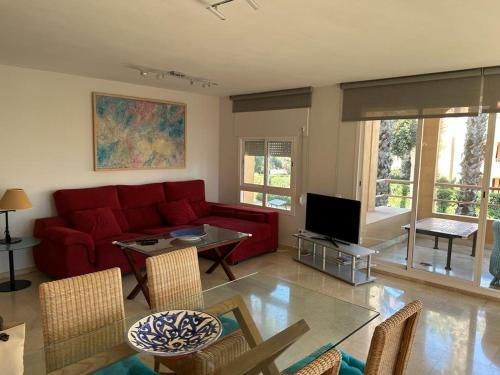 Una sala de estar con un sofá rojo y un televisor. en Charming 3 Bedroom apartment with sea view in the heart of Sotogrande, en Sotogrande