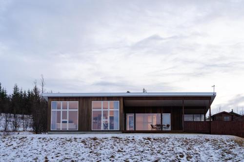 a modern house with a glass facade in the snow at Golden Circle Villa - Hot Tub & Sauna in Fludir