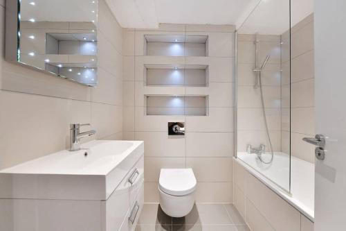 a bathroom with a toilet and a sink and a tub at 1 Bed Apartment moments from Kings Cross Station! in London