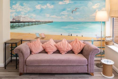 un divano in soggiorno con un dipinto di una spiaggia di Sunny Queens Park Home - Garden & Private Parking a Brighton & Hove
