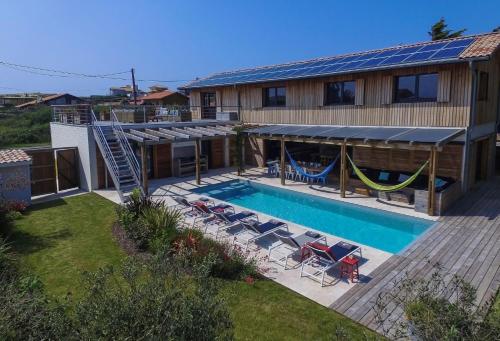 une maison dotée d'une piscine avec des chaises et un hamac dans l'établissement 106 Beach House, à Soorts-Hossegor