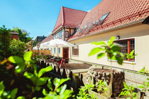 a building with a patio with tables and an umbrella at Hotel & Restaurant Hubertus Sehnde in Sehnde