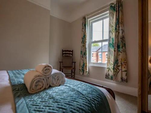 1 dormitorio con toallas en una cama con ventana en Pass the Keys Two bedroom Victoria Town house, easy walk of town en Shrewsbury