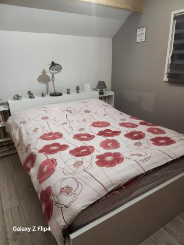 um quarto com uma cama com flores vermelhas em les oliviers em Veigné