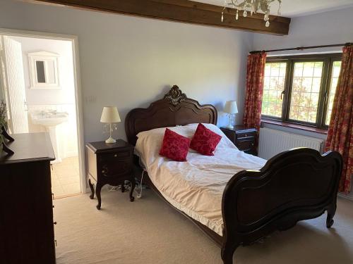 a bedroom with a bed with red pillows on it at Lower Penrose Old Farmhouse Cottage in Launceston