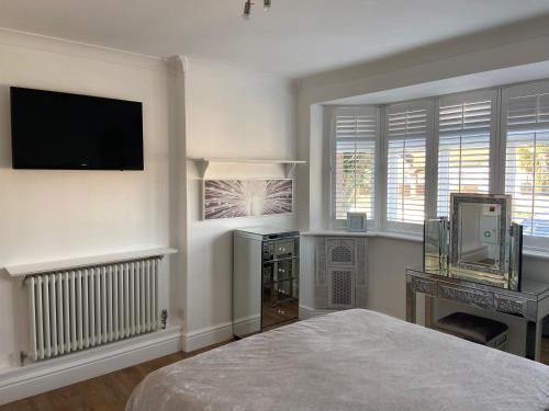 um quarto com uma cama, uma secretária e uma televisão em Botany Bay view Seaside Home em Broadstairs