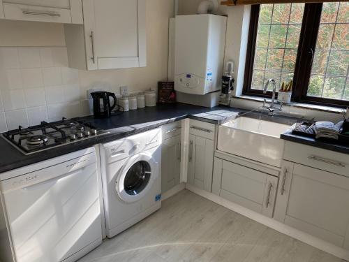 a kitchen with a washing machine and a sink at Lower Penrose Old Farmhouse Cottage in Launceston