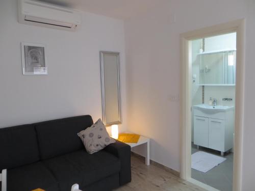 een woonkamer met een zwarte bank en een wastafel bij Apartment Nava in Dubrovnik