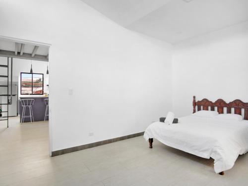 een slaapkamer met een bed en een witte muur bij Casa Bellavista Suites in San José