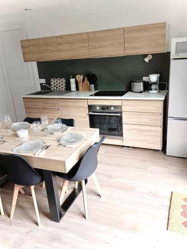 une cuisine avec une table avec des chaises et un réfrigérateur dans l'établissement Les trois chalets - jardin terrasse 7 personnes - Saint Mamet Luchon, à Saint-Mamet