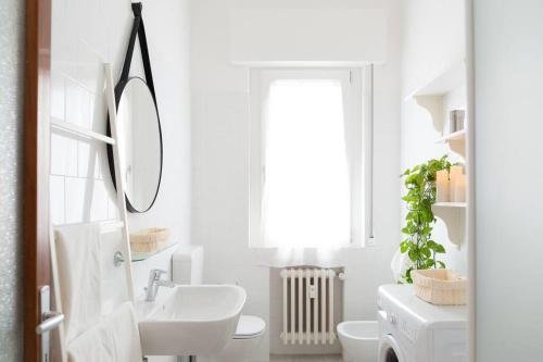 La salle de bains blanche est pourvue d'un lavabo et d'un miroir. dans l'établissement Vintage Apartment Venetian Mood, à Mestre