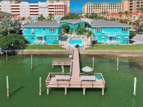 a dock in a body of water with blue houses at Mandaly Bay Efficiency Comfort in Clearwater Beach