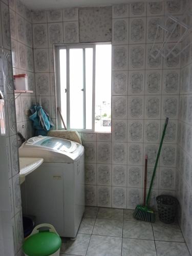 ein Bad mit einer Waschmaschine und einem Fenster in der Unterkunft Apartamento para temporada in Mongaguá