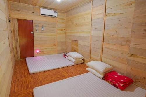 2 Betten in einem Zimmer mit Holzwänden in der Unterkunft Homstay Hưng Yên - Long Cốc 