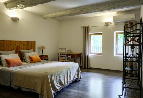 a bedroom with a bed and a desk and two windows at Mas d'Alaure B&B in Verquières