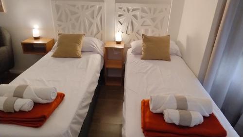2 camas en una habitación con sábanas blancas y toallas en Studio Soho 53 en La Plata