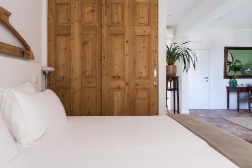 a bedroom with a white bed and a wooden door at Altanure Almatere - Food Forest Boutique Stay in Tavira
