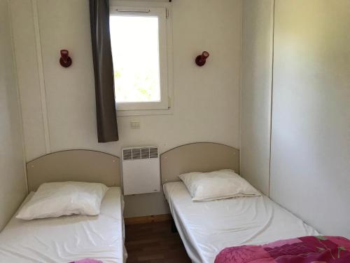 two beds in a small room with a window at Le Domaine du Scorff - hébergements insolites chalets 4 à 6 personnes et roulottes in Kernascléden