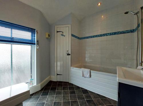 uma casa de banho com uma banheira, um chuveiro e um lavatório. em Salt Marsh Apartment em Tywyn