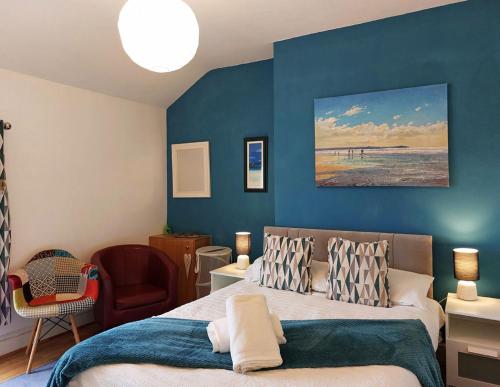 um quarto com uma cama e uma parede azul em Salt Marsh Apartment em Tywyn
