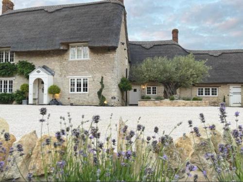 una gran casa de piedra con flores delante en Greystone Guesthouse en Titchmarsh