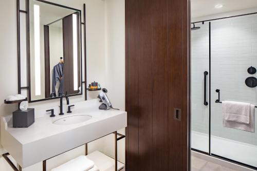 a bathroom with a sink and a mirror at Canopy By Hilton Charlotte SouthPark in Charlotte
