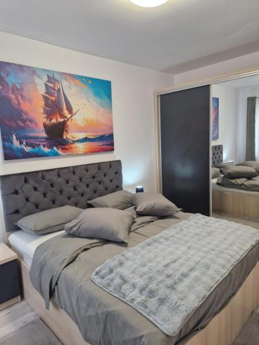 a bedroom with a large bed with a painting on the wall at Casa ALEX in Apărătorii Patriei