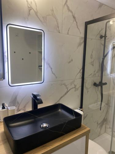 W łazience znajduje się czarna umywalka i prysznic. w obiekcie Le Bastidon des Alpilles w mieście Saint-Étienne-du-Grès