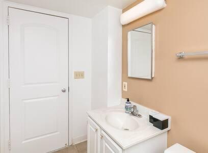 a white bathroom with a sink and a mirror at 2BR Chic Executive Apartment in Prime Location in Arlington