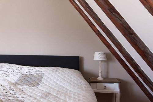 a bed with a white comforter and a table with a lamp at Bed & Breakfast De Stolp in Zuidoostbeemster
