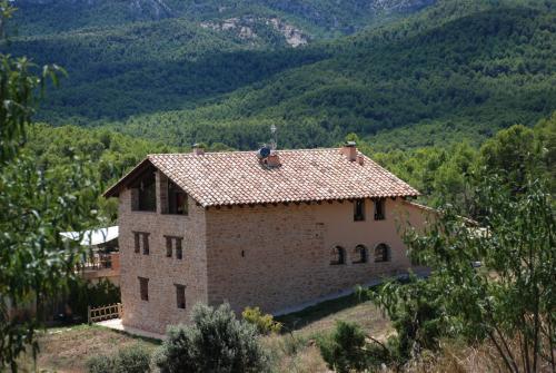 a house on a hill with mountains in the background at Masia de la Serra de la Cogulla in Peñarroya de Tastavins