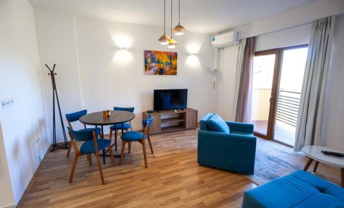 sala de estar con mesa y sillas azules en Happy Home Apartments, en Mavrovi Anovi