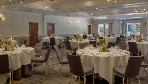 a banquet room with white tables and chairs at DoubleTree by Hilton St. Anne's Manor in Bracknell