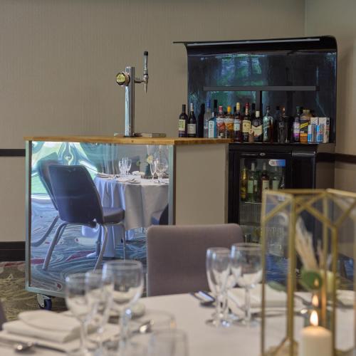 a dining room with a table with wine glasses at DoubleTree by Hilton St. Anne's Manor in Bracknell