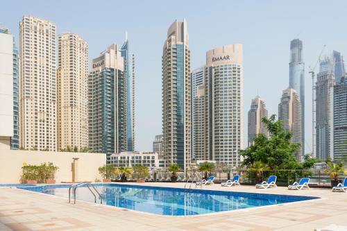 a pool in front of a city skyline with tall buildings at Chic Apartment Dubai Marina in Dubai