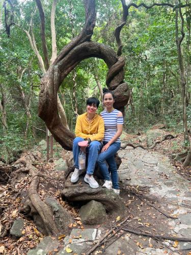 dos personas sentadas en un tronco de árbol en el bosque en Uyen's House en Con Dao