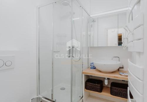uma casa de banho com uma cabina de duche em vidro e um lavatório. em 1 Mirabeau C.L.S Deauville em Deauville